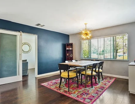 Dining room before with a flat navy accent wall and a busy patterned area rug