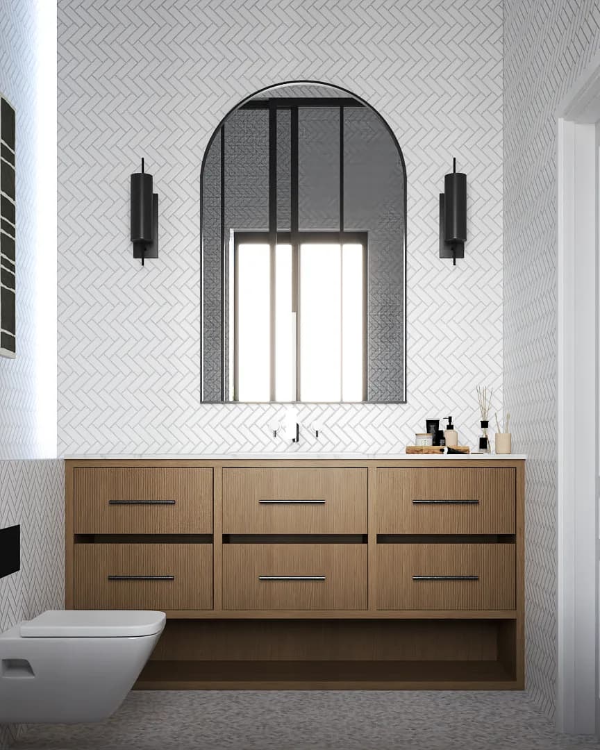 Oak floating six-drawer vanity below an arched iron mirror and black sconces on white herringbone tile.