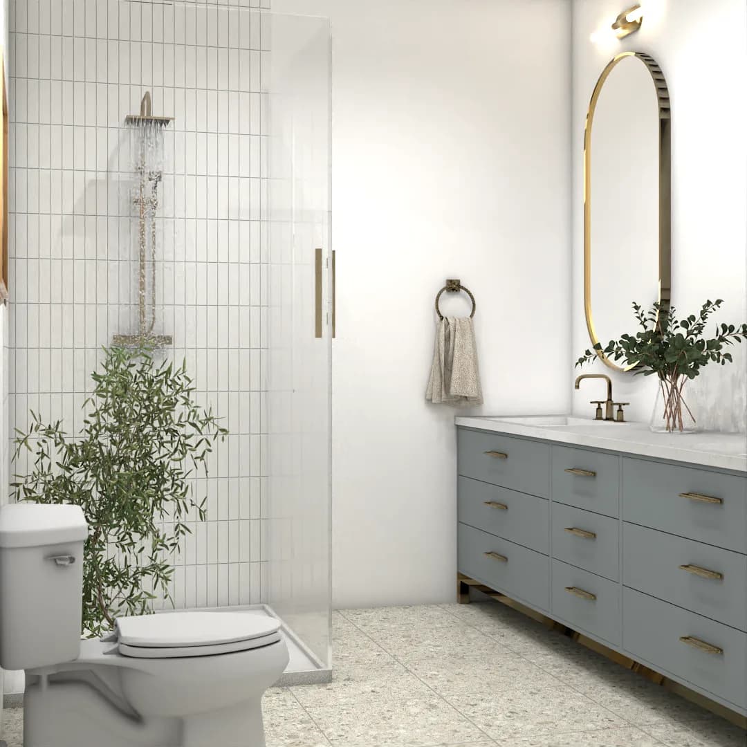 Transitional bathroom with blue-gray shaker vanity, gold oval mirror, terrazzo floor, and glass shower enclosure with brass fixtures