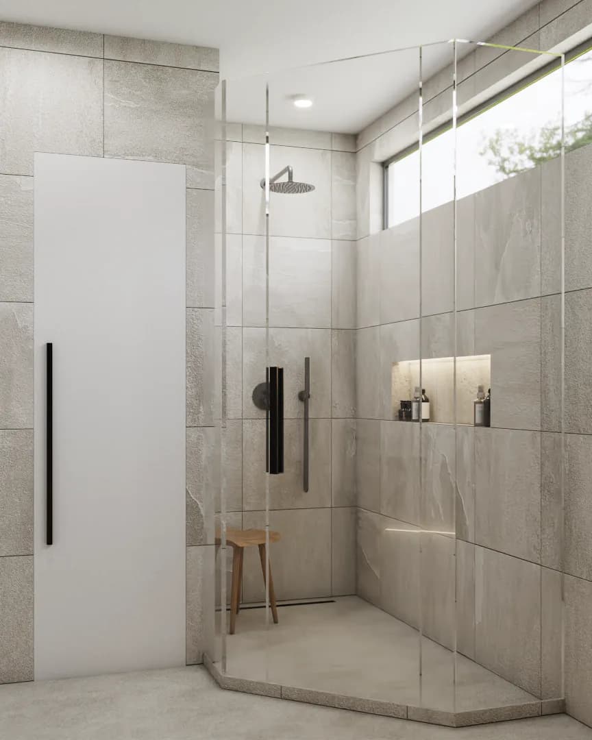 Corner walk-in rain shower with frameless glass, gray stone tile walls and floor, built-in niche, and wooden stool