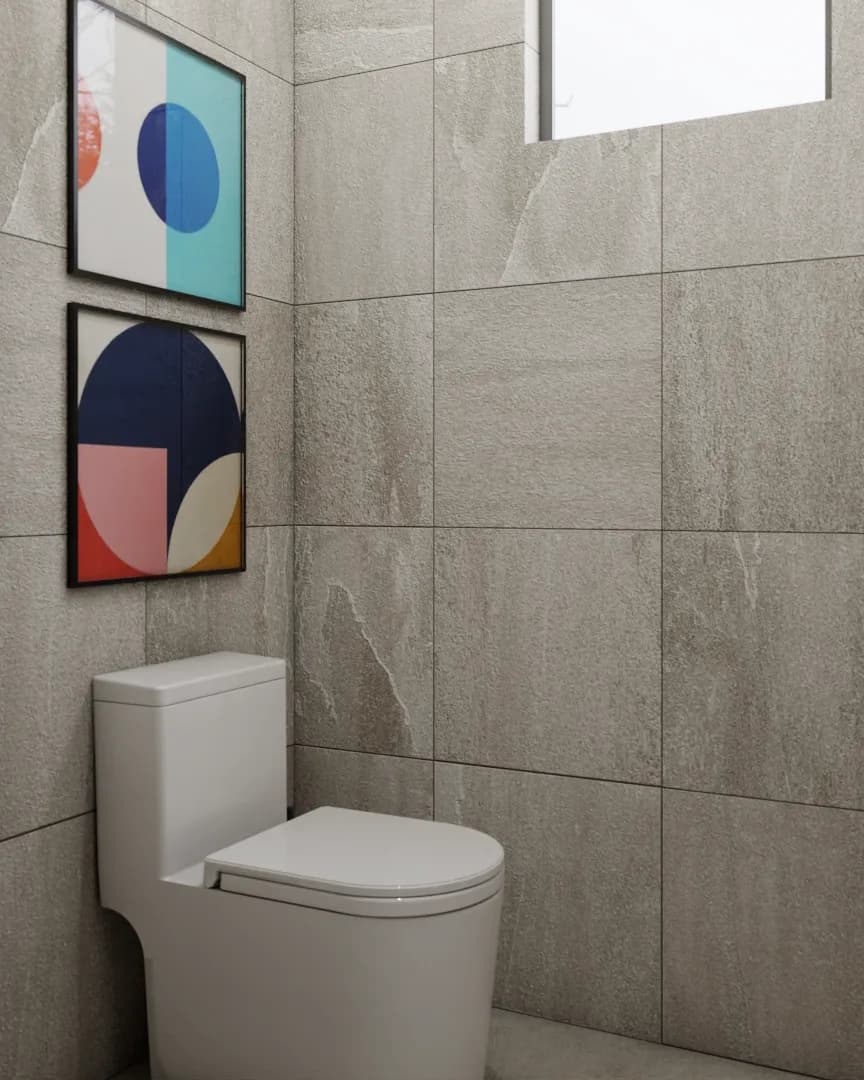 Toilet alcove with bold geometric abstract art in teal and coral against gray stone tile wall