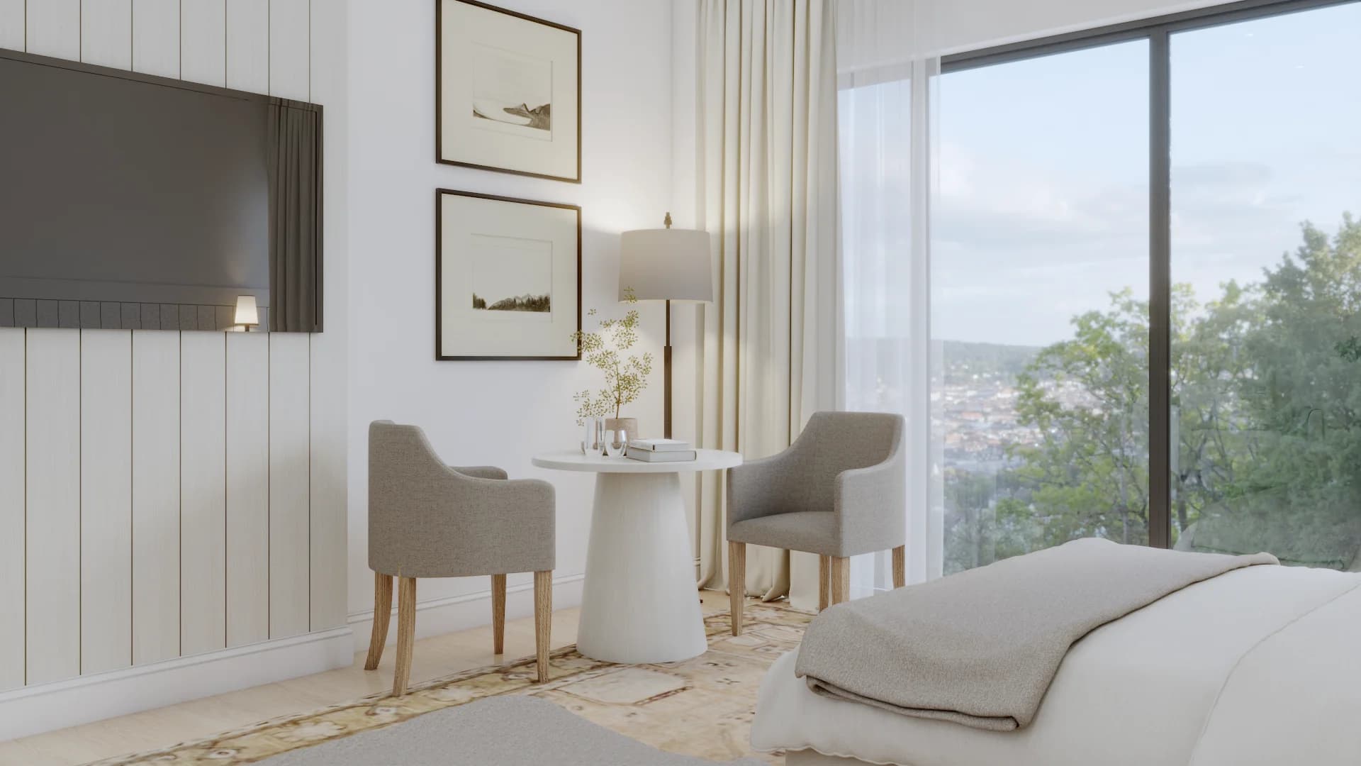 Bedroom sitting nook with wall-mounted TV on shiplap panel, two taupe armchairs around white pedestal table, landscape art, and floor-to-ceiling garden-view windows