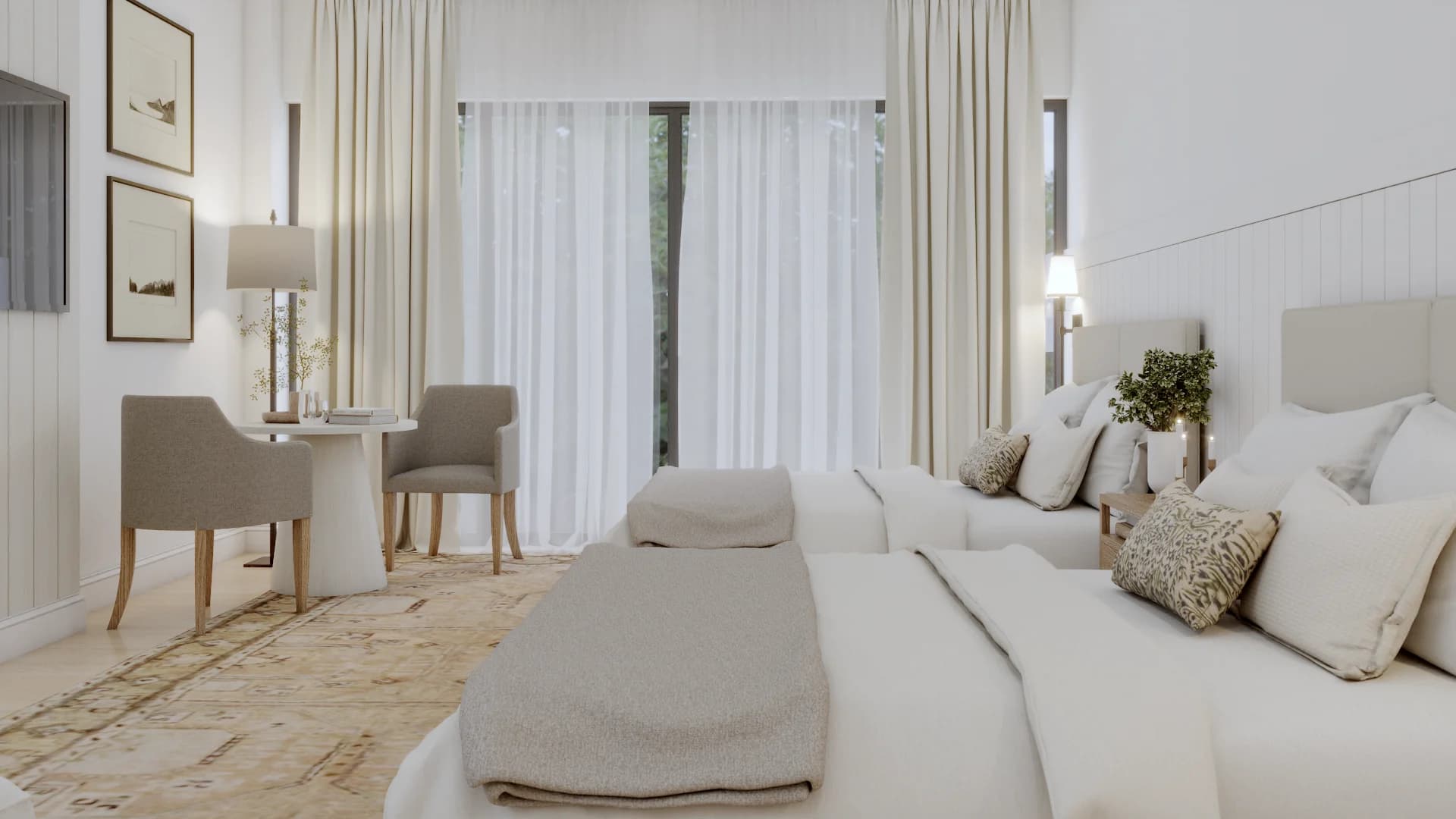Transitional cream bedroom with two upholstered beds side by side, shiplap wall behind, wall sconces, two taupe armchairs around a white pedestal table, framed landscape art, floor lamp, vintage rug, and garden views by Debora Interiors