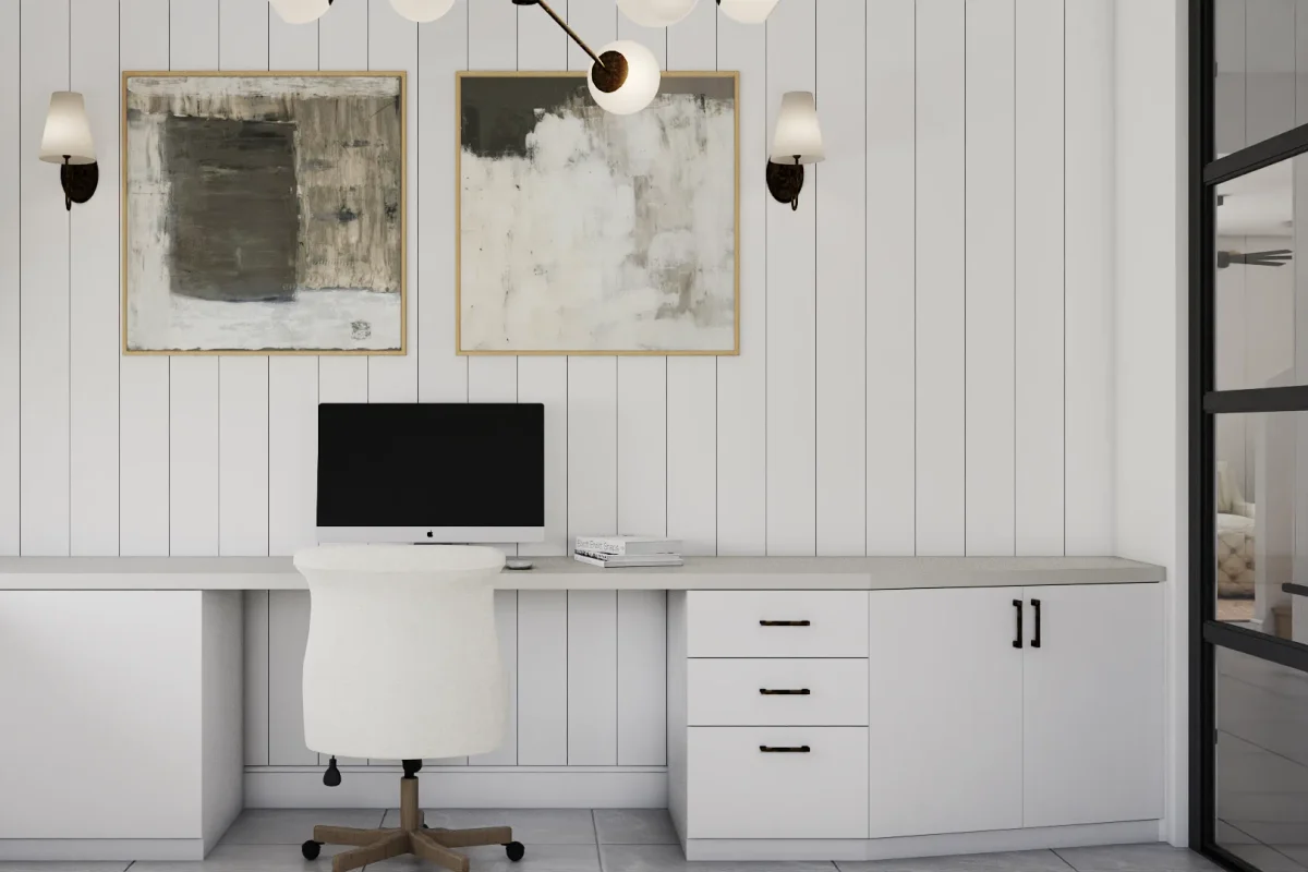White built-in desk running full wall width against white shiplap, black bar hardware on three-drawer pedestal and cabinet, two gold-framed abstract artworks, and wall sconces
