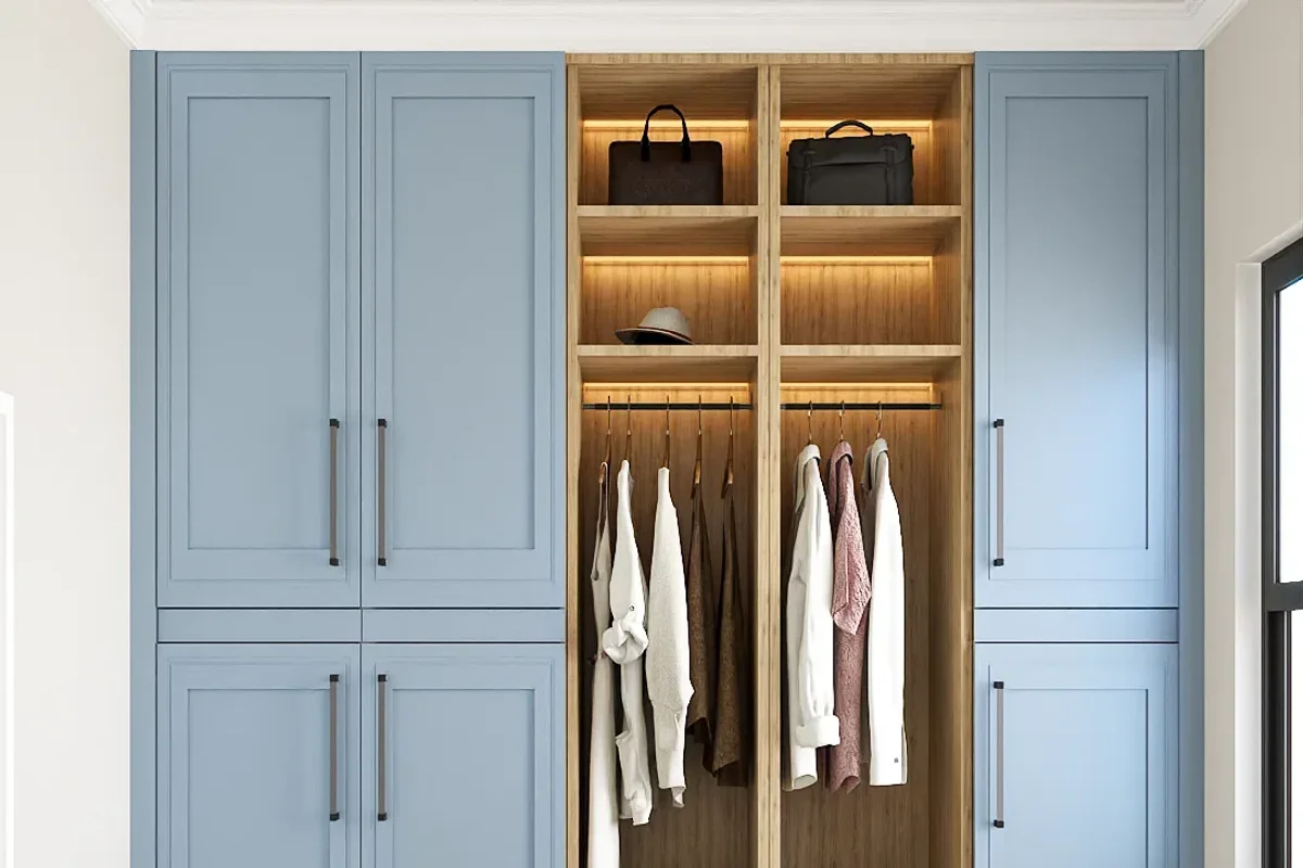 Powder blue shaker built-in wardrobe with LED-lit oak center section, open shelves holding bags and a hat, hanging rail with clothes, and brushed bar handles