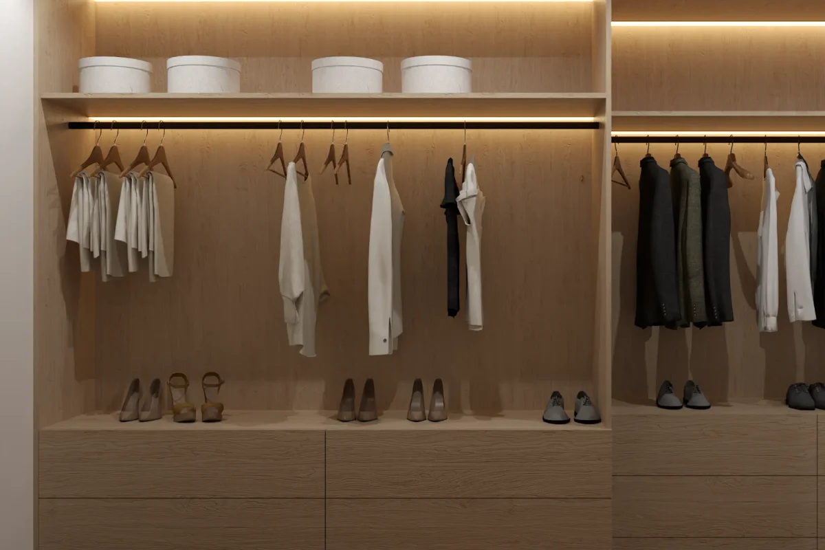 Wide open walk-in wardrobe with full-width oak hanging rails, flush drawer bank below, open hat box shelf at top, and warm LED cove lighting at the ceiling