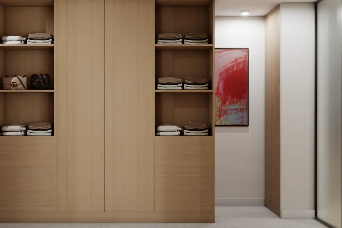 Tall built-in oak wardrobe with a central flush-panel column divider, symmetric open shelving bays with folded clothes and bags, flat base drawers, and a hallway with red abstract art beyond