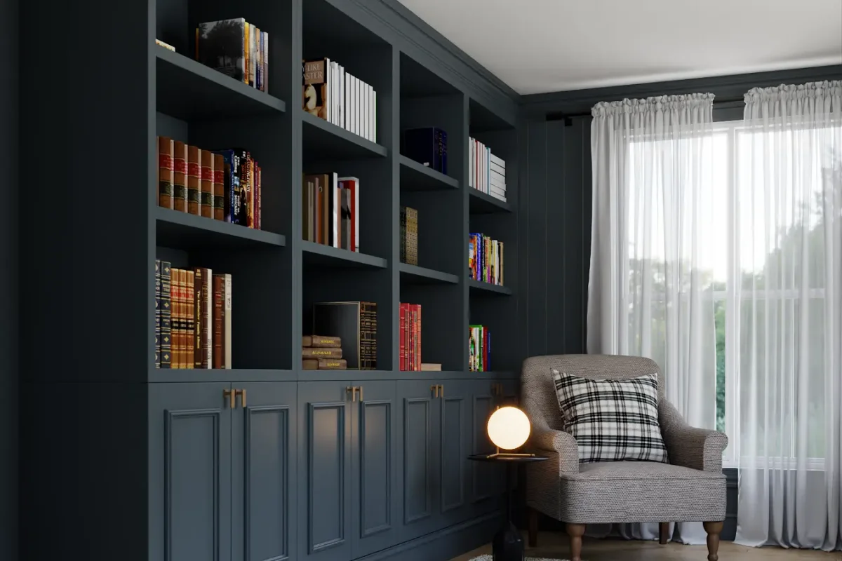 Deep navy built-in floor-to-ceiling library bookcases with raised panel wainscoting base, filled with books, next to a plaid armchair and globe floor lamp in a moody reading room