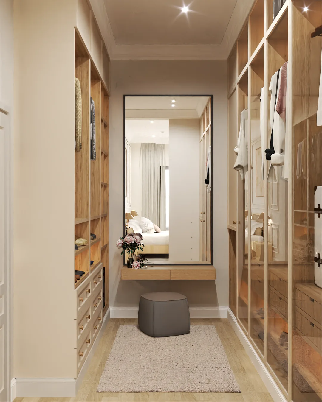 Walk-in closet end wall with full-length black-frame floor mirror reflecting the adjacent bedroom, square pouf ottoman, floating oak vanity desk, and glass-front shelving on both sides