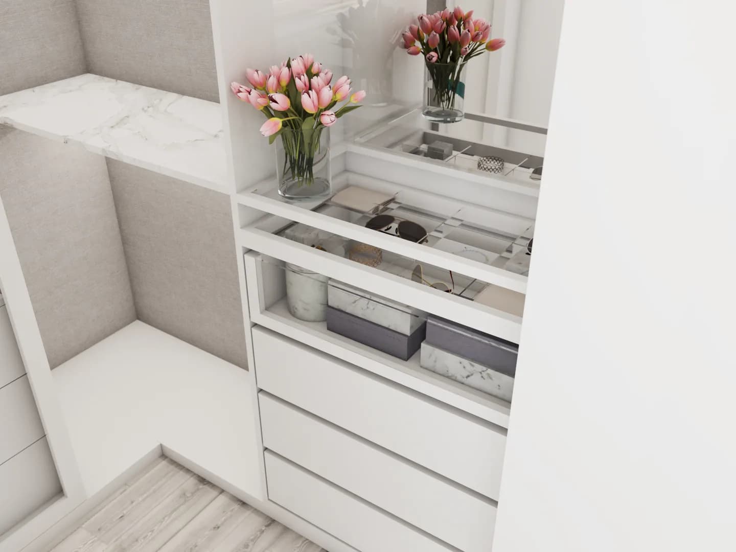 Close-up of white closet vanity with marble surface, glass-lid compartment tray for sunglasses, stacked gray and marble storage boxes, and pink tulip arrangement reflected in the mirror.
