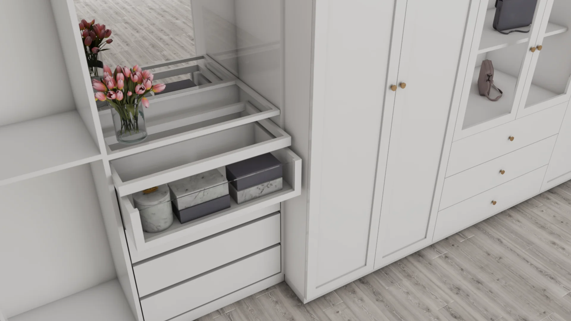 White built-in closet with open pull-out drawers holding marble and gray storage boxes, a candle jar, and pink tulips in a glass vase, beside a wardrobe with brass knobs and handbag shelf.