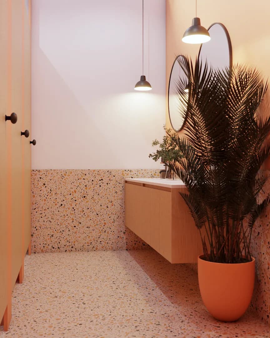 Terrazzo restroom with pink partition, floating oak vanity, oval mirror, and palm plant