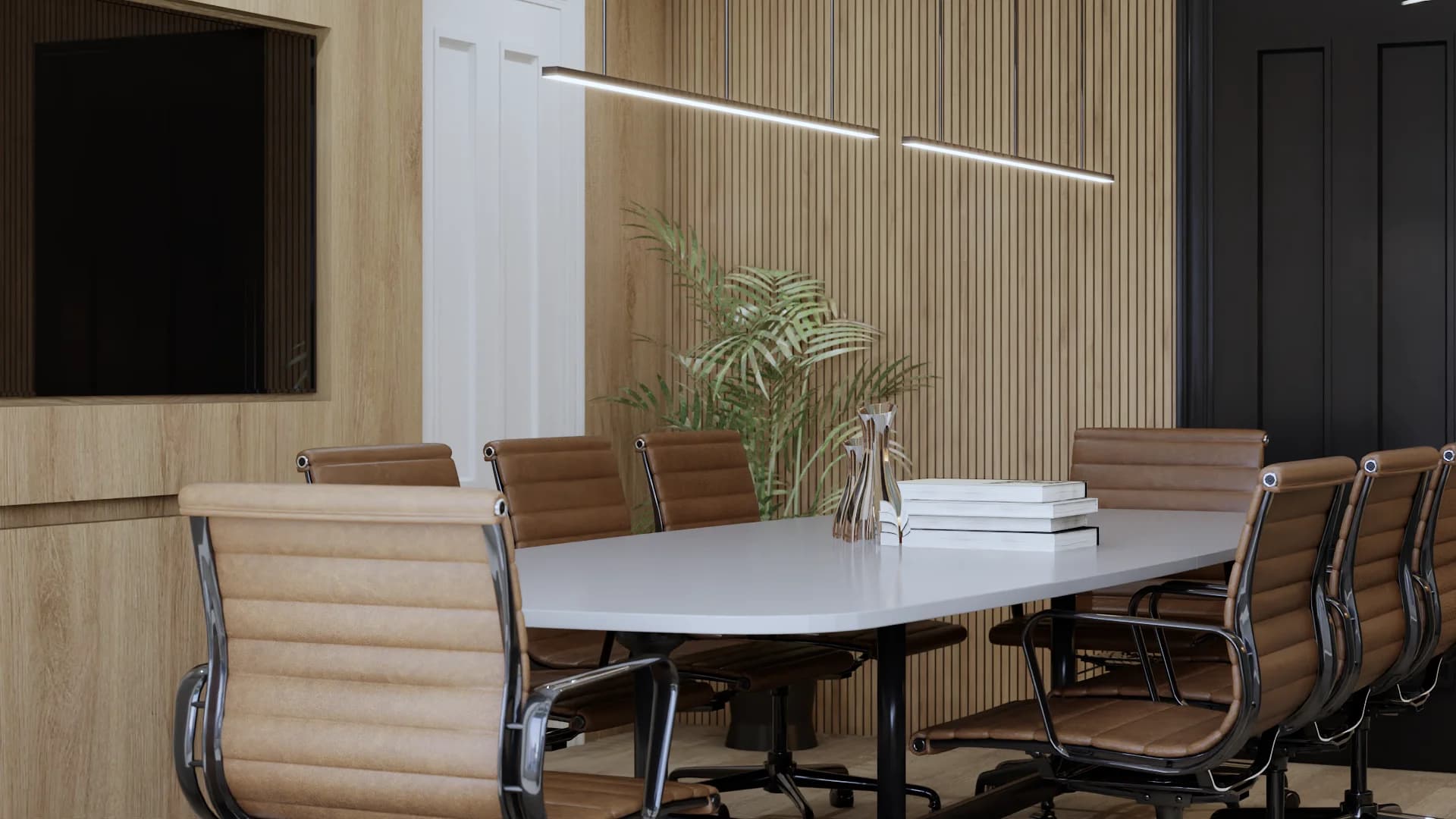 White oval conference table with six tan leather executive chairs on chrome bases, two staggered linear LED pendant lights overhead, vertical oak wood slat accent wall, large potted tropical palm in corner, stacked white books as centerpiece, wall-mounted TV panel on left