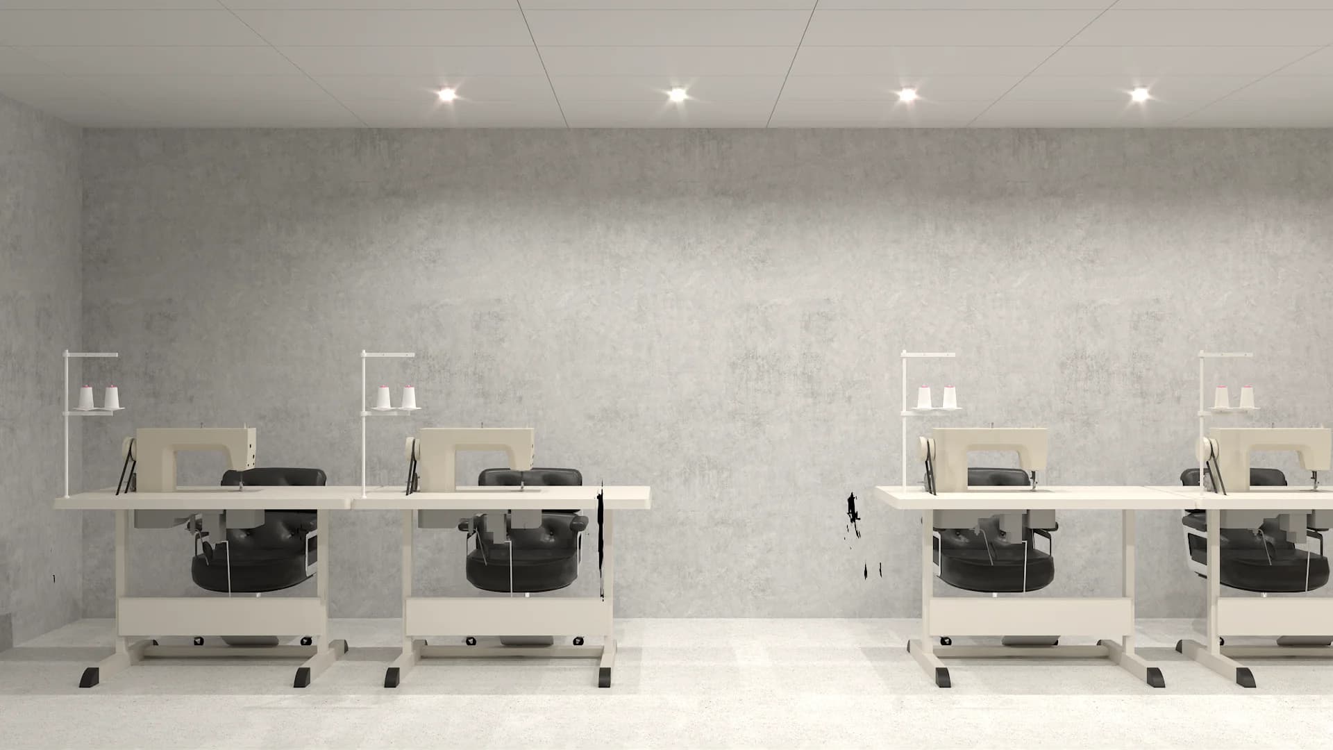 Four industrial sewing machine stations on white tables with black chairs against concrete wall