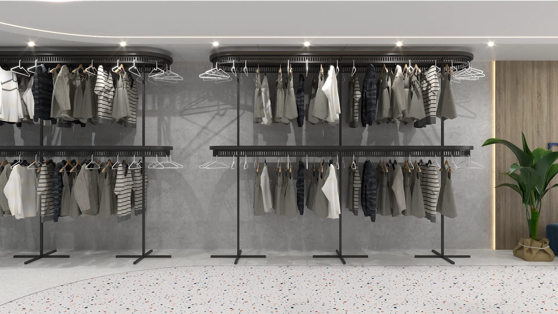 Two-tier black metal clothing racks filled with garments against gray concrete wall