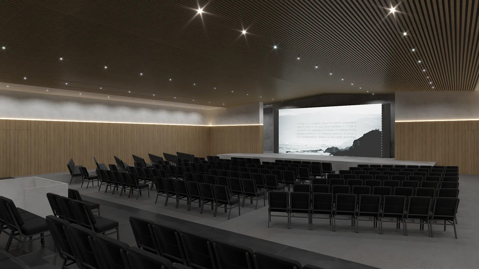 Concrete stage platform with projection screen and black seating rows from the rear