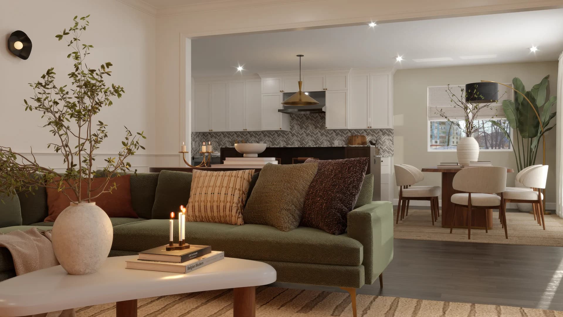 Open plan living room with green velvet sectional, walnut oval dining table, cream chairs, white kitchen with herringbone backsplash, wainscoting panels, and brass fixtures