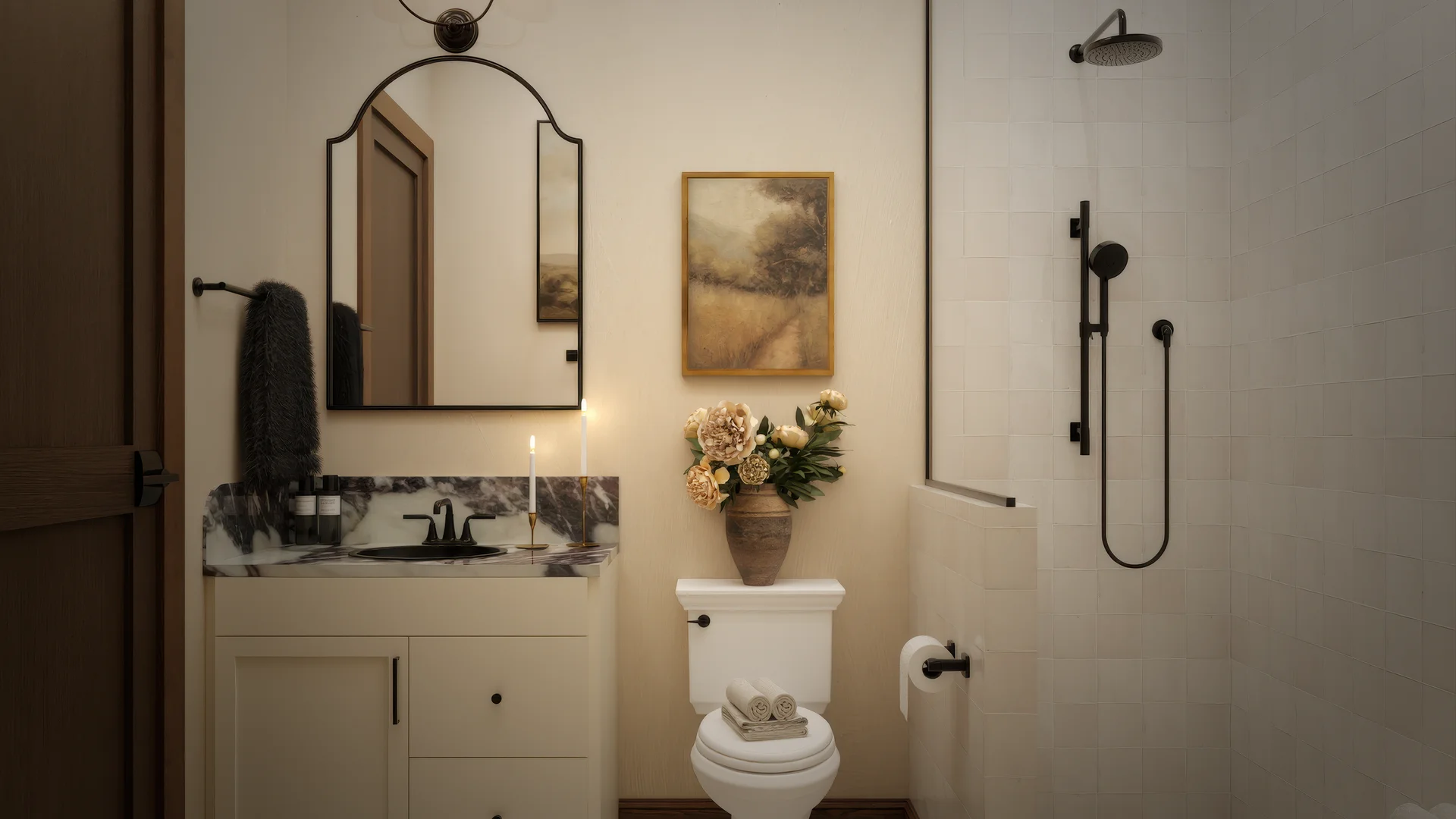 Guest bathroom with arched iron mirror, cream vanity with marble top, black faucet, landscape painting, dried hydrangeas, walk-in shower with black fixtures, and star mosaic floor