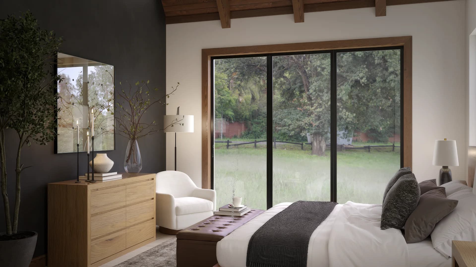 Guest bedroom with charcoal accent wall, oak dresser with mirror and dried branches, white accent chair, vaulted wood ceiling with black chandelier, and sliding glass doors