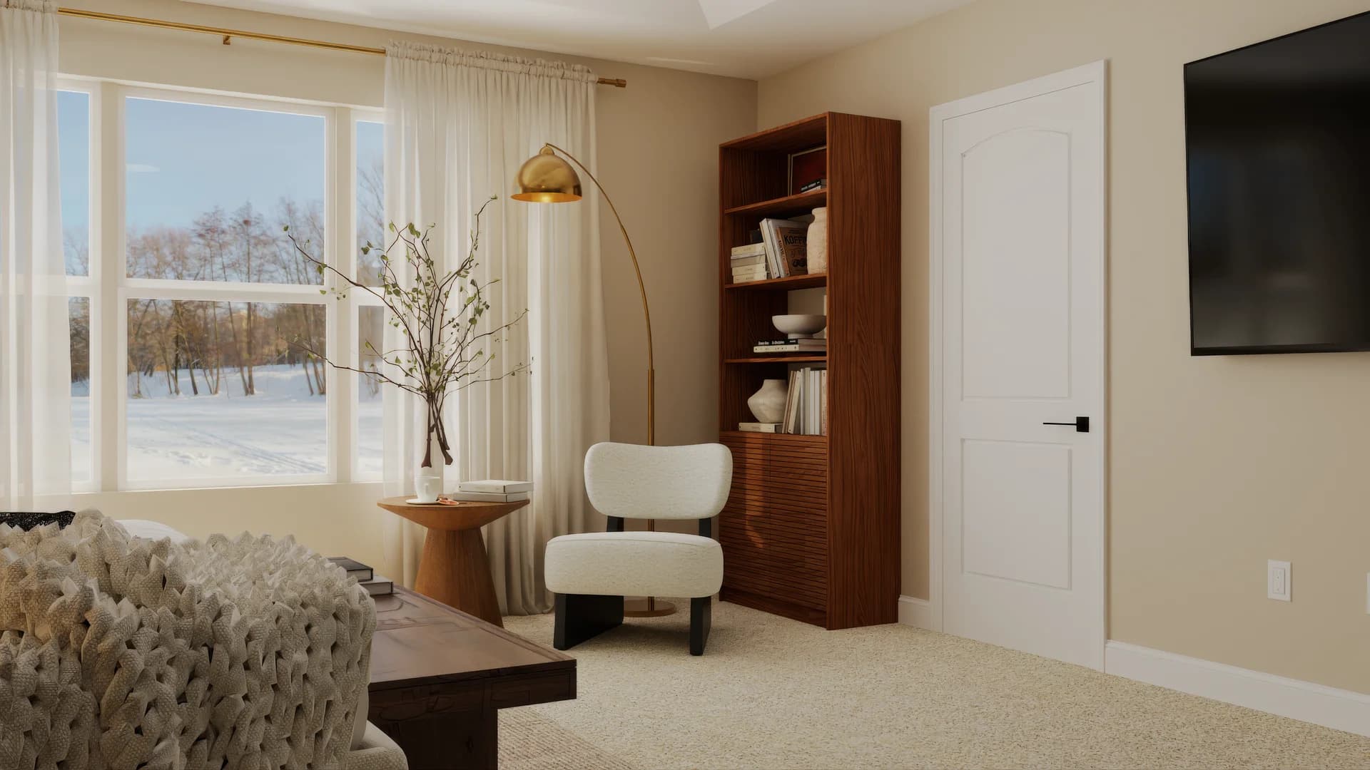 Master bedroom sitting area with wall-mounted TV, walnut open bookshelf with ceramics and books, white boucle accent chair with black legs, brass arc floor lamp, walnut pedestal side table with dried branches, sheer curtains, and partial view of knit throw on sofa.
