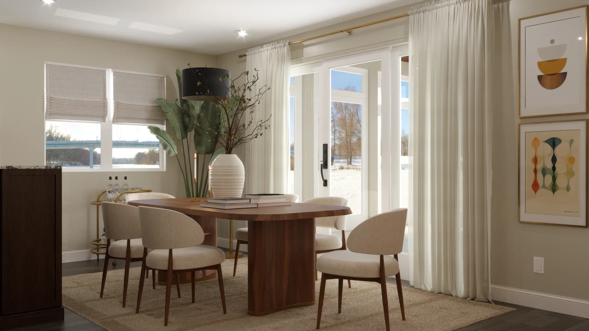 Full dining room with oval walnut pedestal table, cream upholstered chairs, ribbed white ceramic vase, brass taper holders, sheer linen curtains, french doors to patio, roman shade, mid-century bird and geometric art prints in gold frames on side wall, jute rug