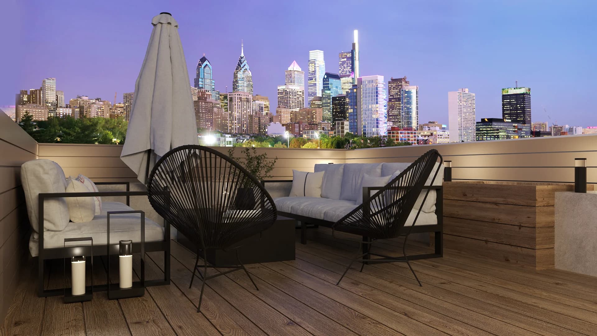 Rooftop terrace at night with Acapulco chairs, folded umbrella, sofa, and Philadelphia skyline