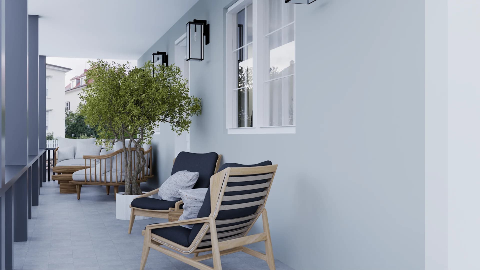 Covered balcony with slatted teak lounge chair, charcoal cushions, olive tree in white cube planter, and black wall sconce against gray-blue stucco walls