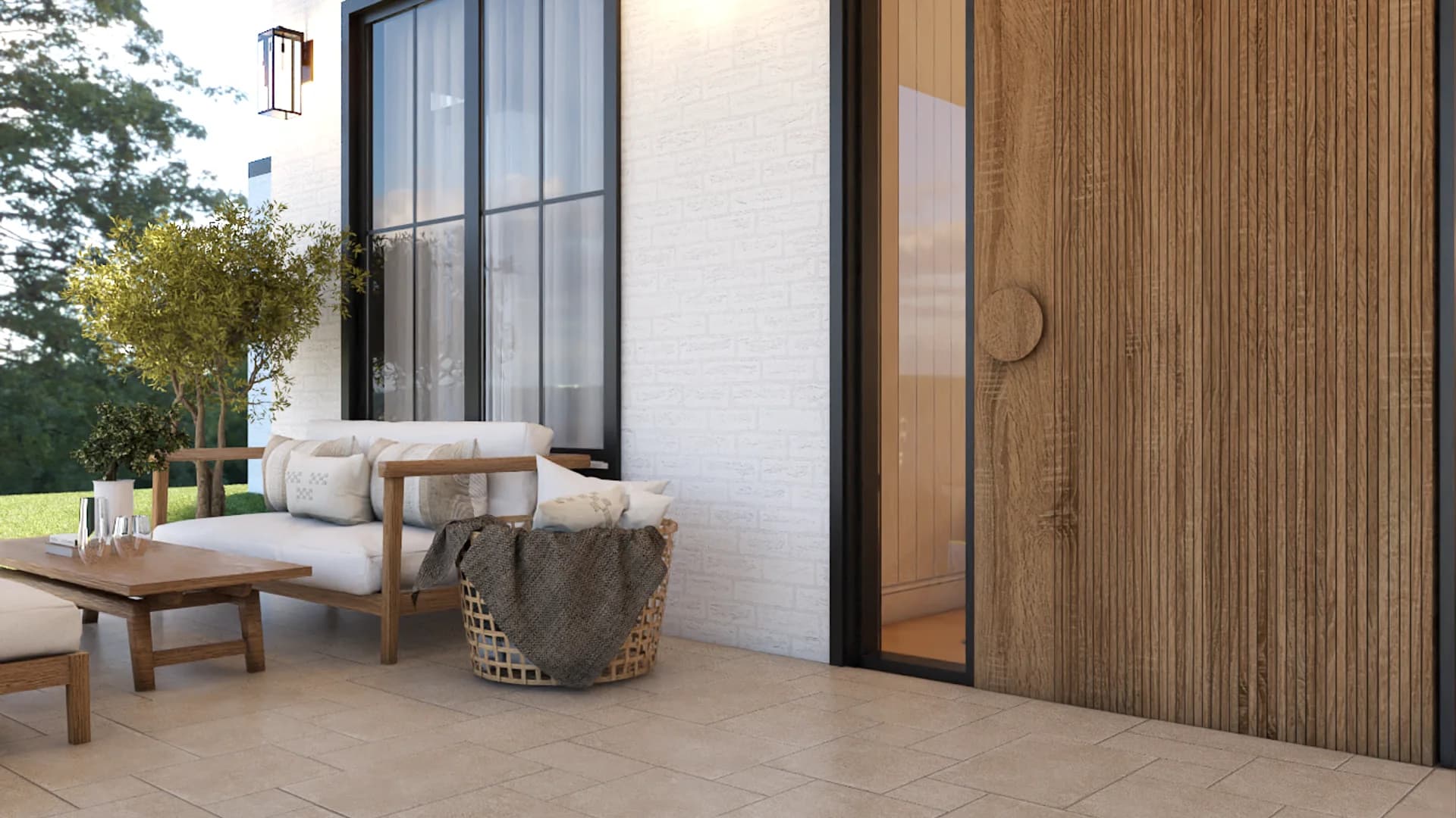 Side yard patio with teak outdoor sofa, wicker lounge chair with fur throw, teak coffee table, white brick wall, black steel-frame windows, and wide wood-slat pivot door by Debora Interiors