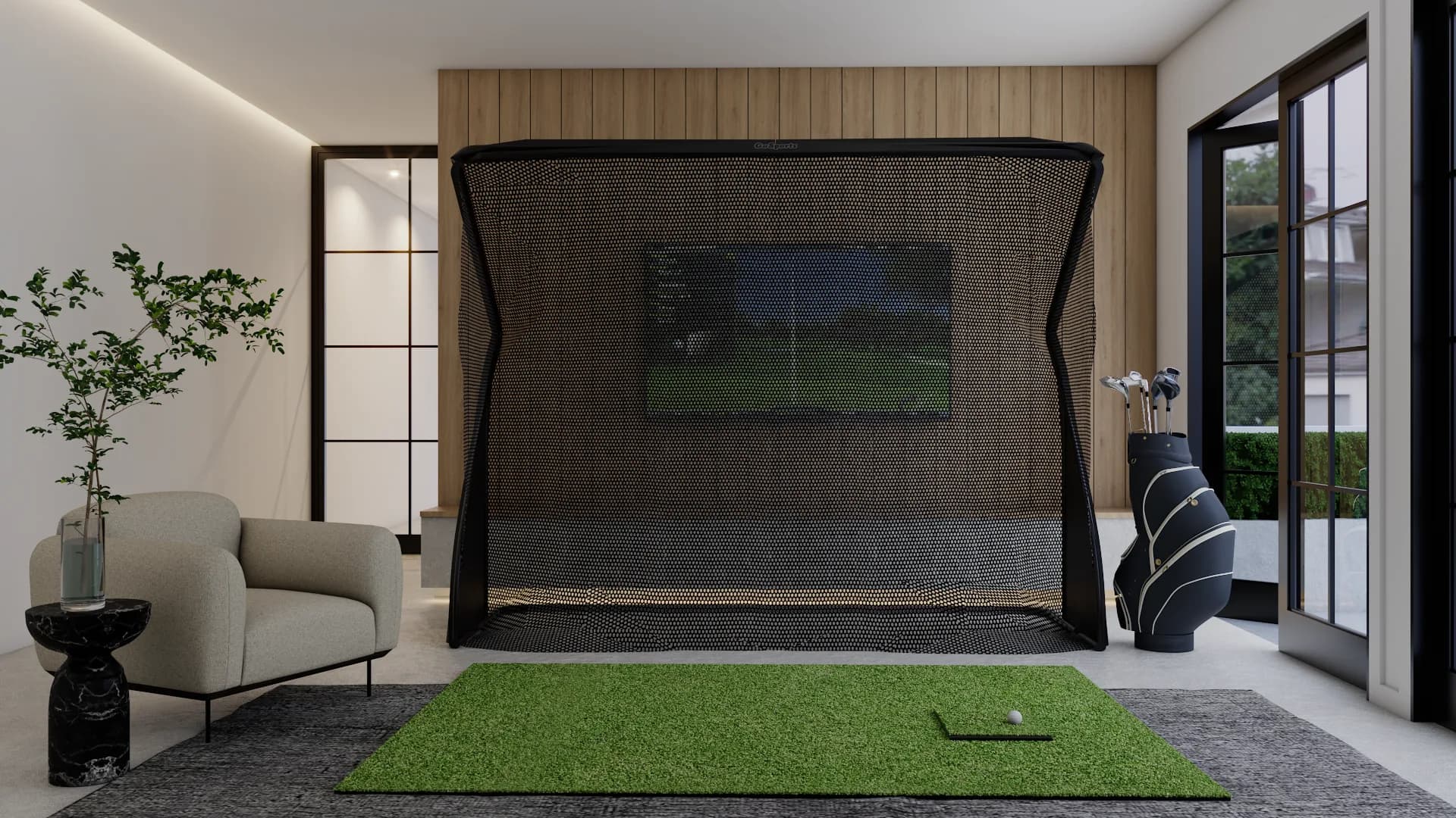 Indoor golf simulator with black net, wood panel wall, green turf mat and lounge chair