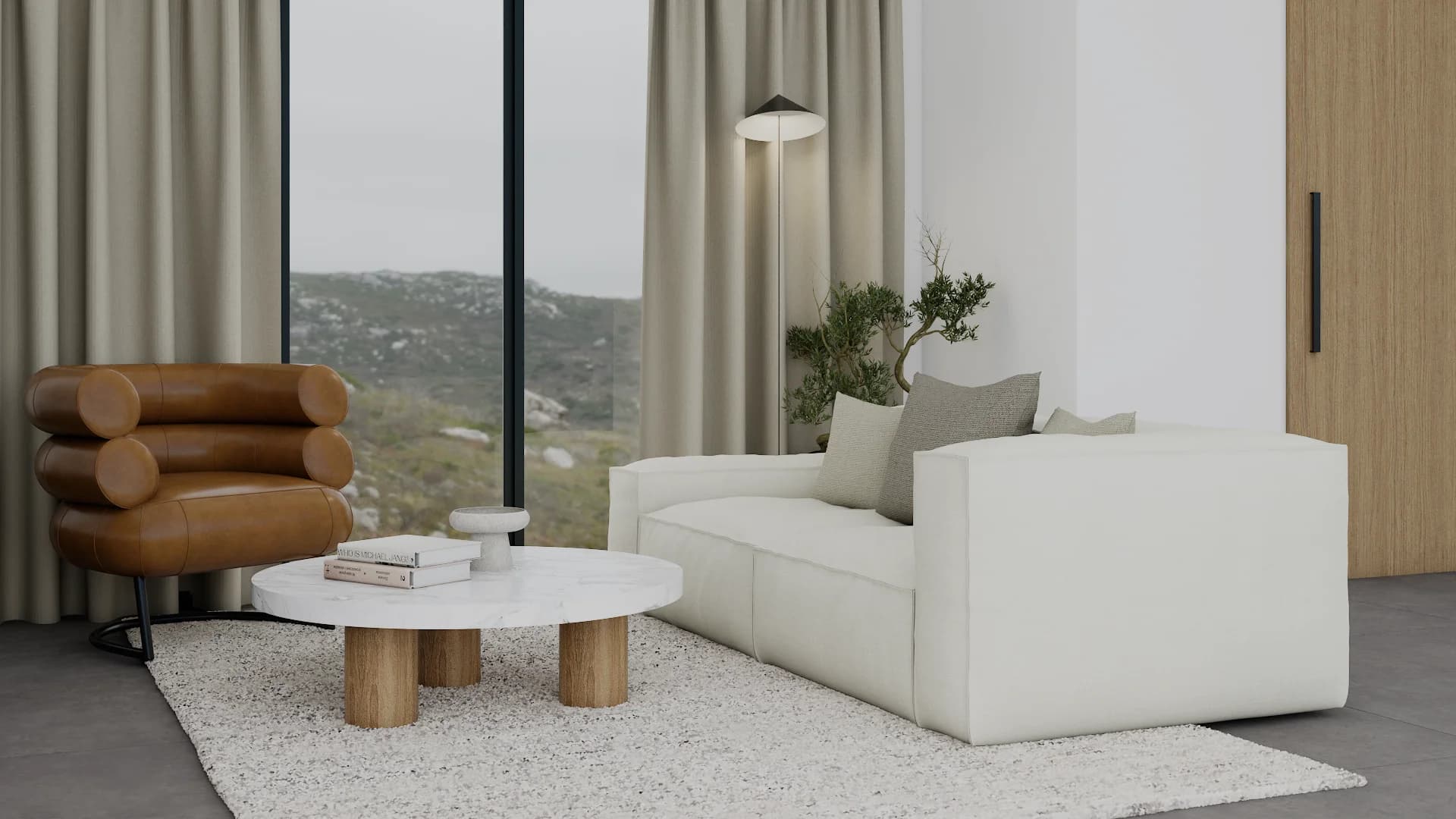 Organic modern living room with white curved sofa, cognac leather armchair, round coffee table, and mountain view