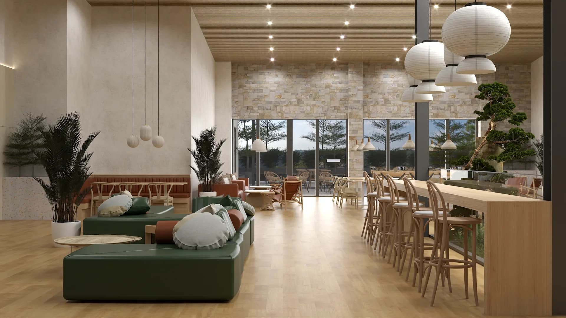 Spacious restaurant interior with a green modular sofa and round cushions in the foreground, a long natural wood bar counter with light wood stools, white paper lantern pendants, exposed stone accent wall, bonsai tree display, and large glass doors opening to an outdoor terrace