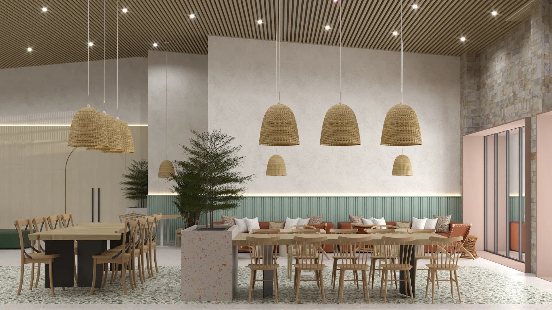Restaurant dining section with four large woven wicker bell pendant lights hanging over a long wooden table with spindle-back chairs, sage green fluted wainscoting on the back wall, slatted wood ceiling with recessed spotlights, and a terrazzo counter divider with a small pine tree