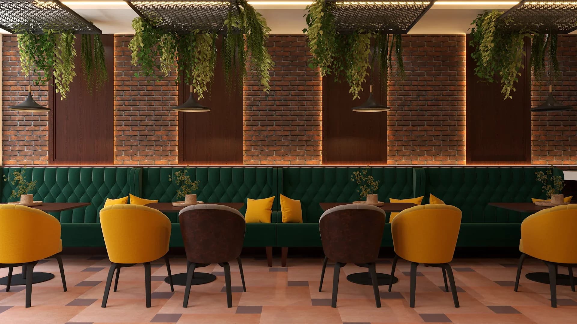 Restaurant wall with exposed red brick panels and dark wood molding, emerald green tufted leather banquette seating with yellow accent pillows, mustard yellow velvet barrel chairs, brown upholstered side chairs, dark round bistro tables, trailing green plants from a perforated metal ceiling, and terracotta tile flooring