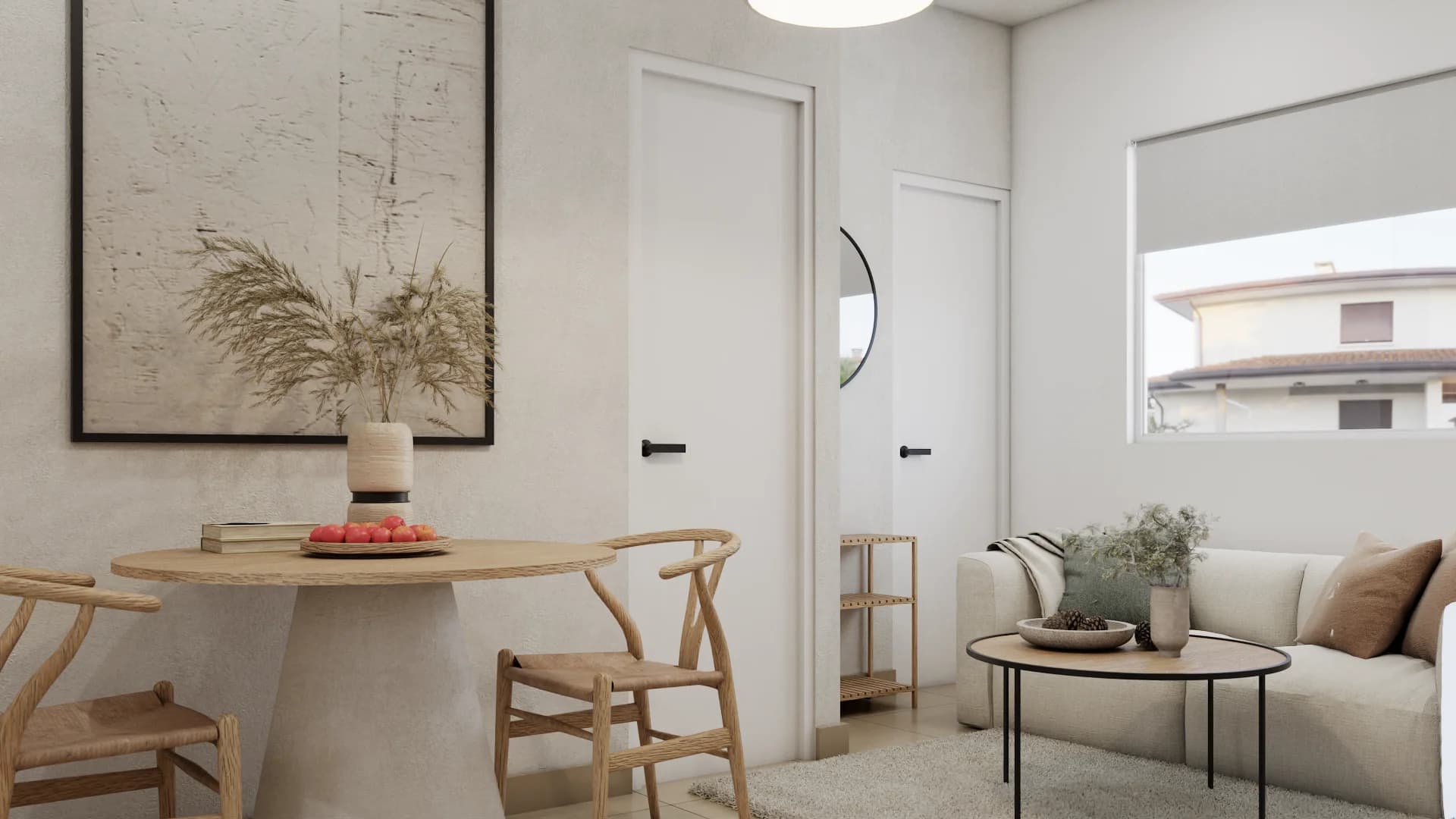 Compact studio apartment with round oak pedestal table, pale wishbone chairs, pampas grass art, and cream sofa beyond