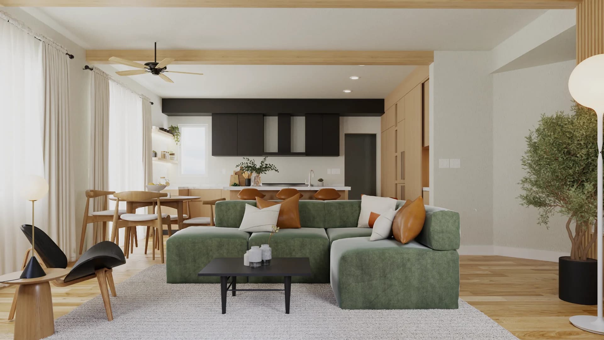 Studio with green velvet sectional, round wood dining table, wishbone chairs, and oak-and-black kitchen behind