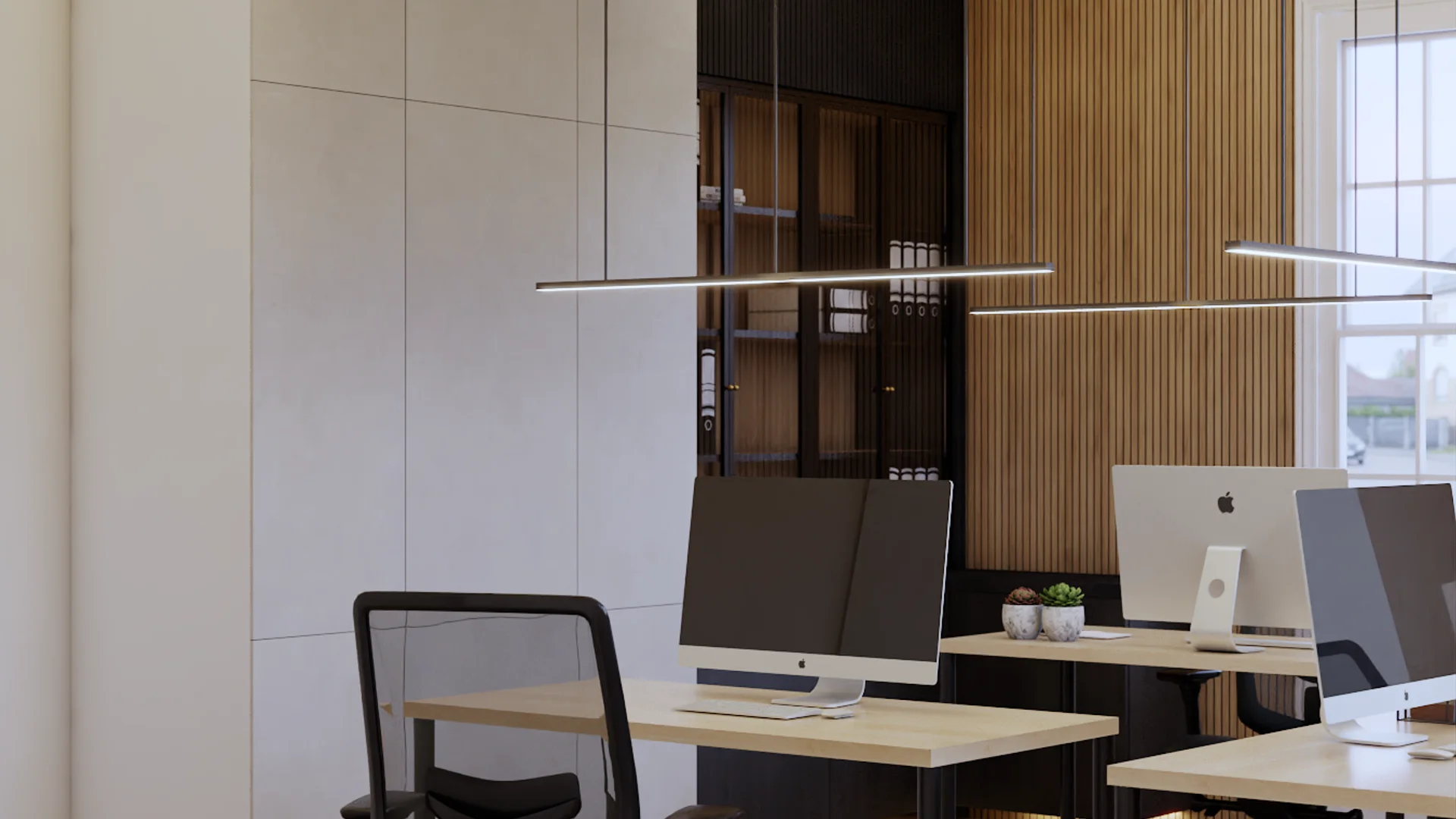 Close-up of maple-top desks with iMac monitors, black mesh chairs, small succulents, adjacent dark-framed glass display cabinet with oak interior holding binders, floor-to-ceiling oak vertical slat accent wall, double linear pendant lights overhead