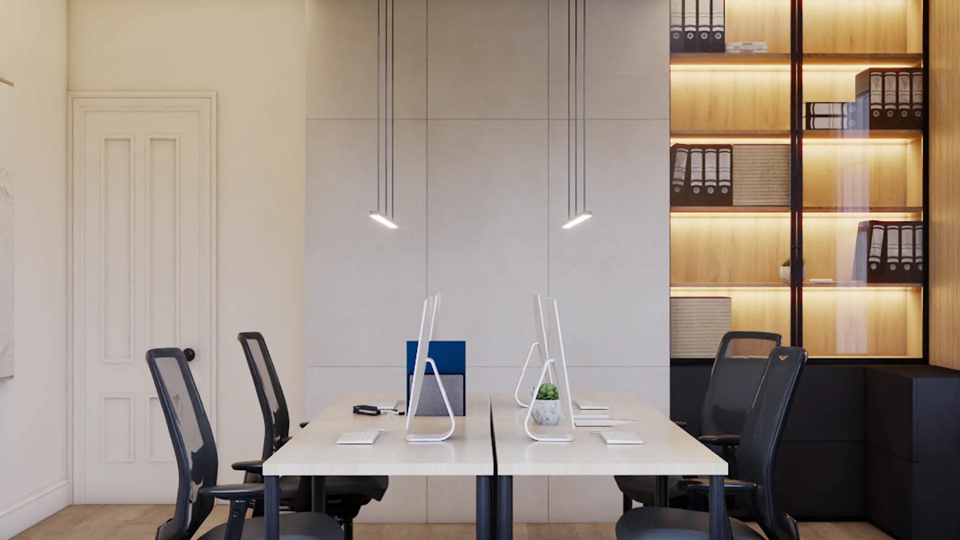 Open office with four-person shared desk, white panel wall, two slim pendant lights overhead, black mesh ergonomic chairs, and a tall oak-framed bookshelf with LED strip lighting holding binders and boxes