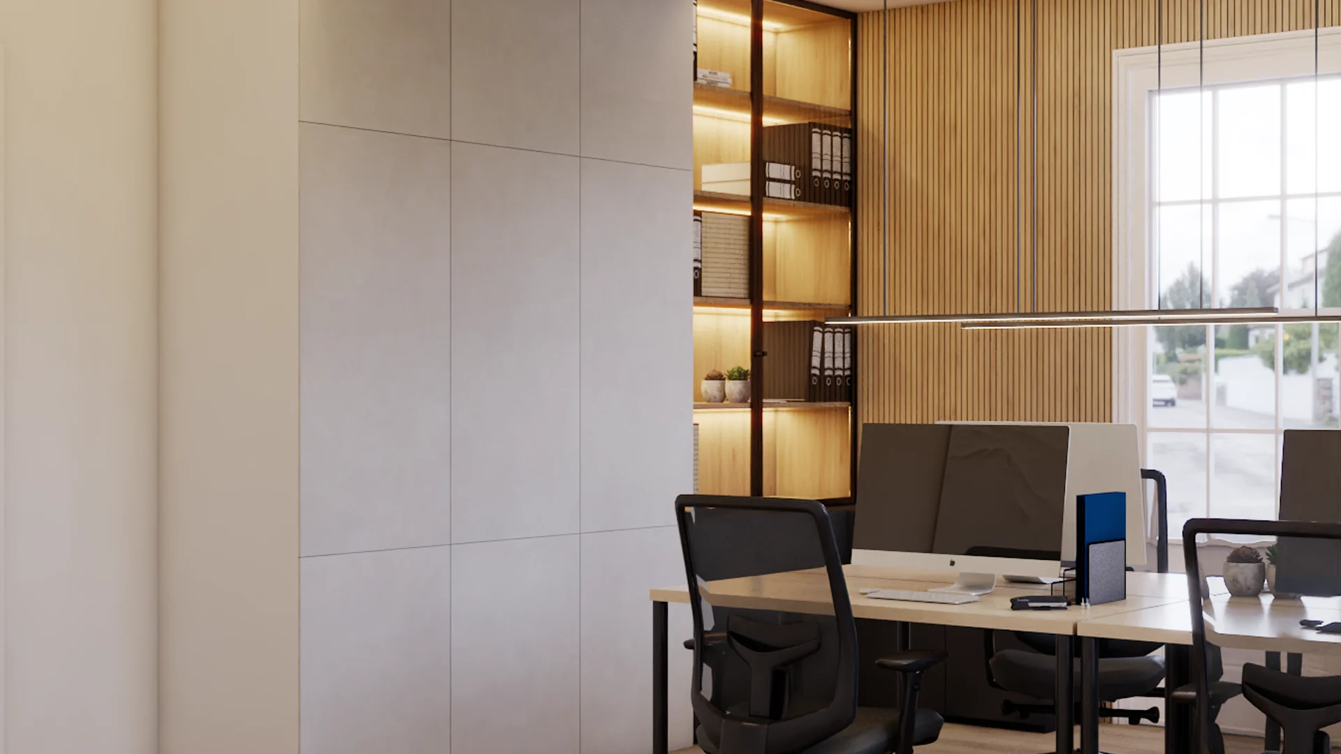 Open office corner showing LED-lit built-in oak bookshelf with binders and storage boxes alongside oak vertical slat accent wall, two maple-top desks with black steel legs, black mesh task chairs, linear pendant light, large grid window