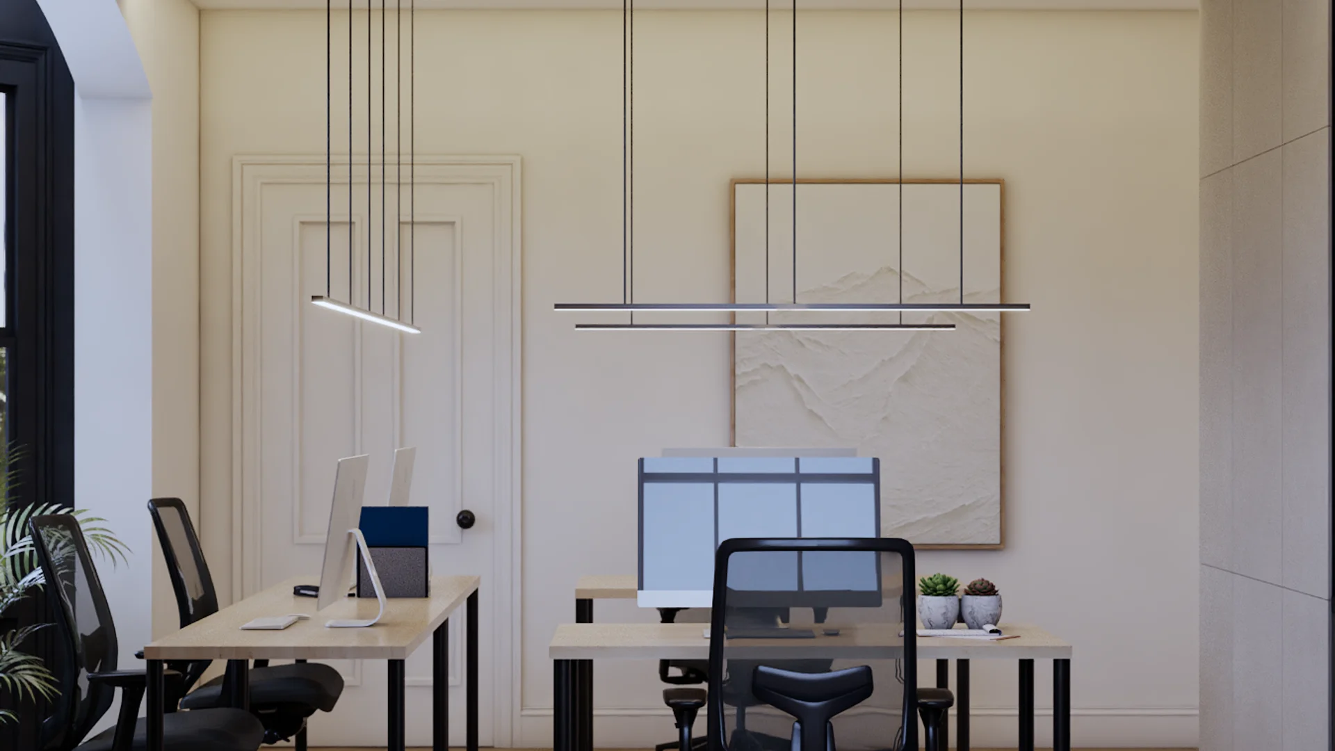 Two-desk office with separate maple-top desks on black legs, black mesh ergonomic chairs, triple-monitor setup at right desk, double staggered linear black pendant lights, cream paneled walls, large textured beige canvas art in oak frame